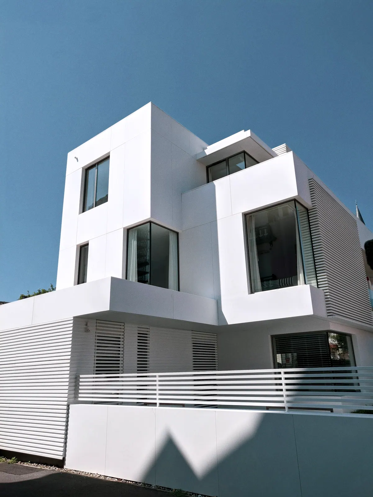 Clôture en acier à lames verticales régulières le long d'une façade contemporaine