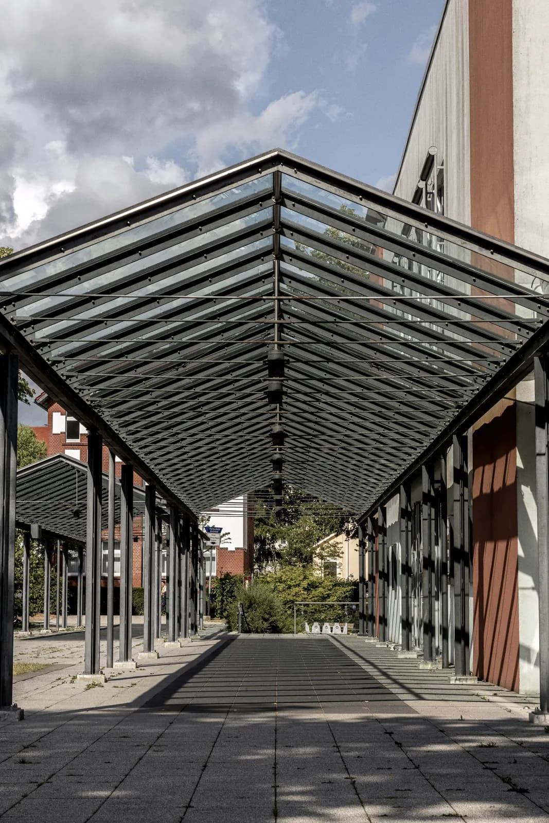 Auvent vitré sur ossature d'acier au-dessus d'un passage, montants réguliers et couverture translucide
