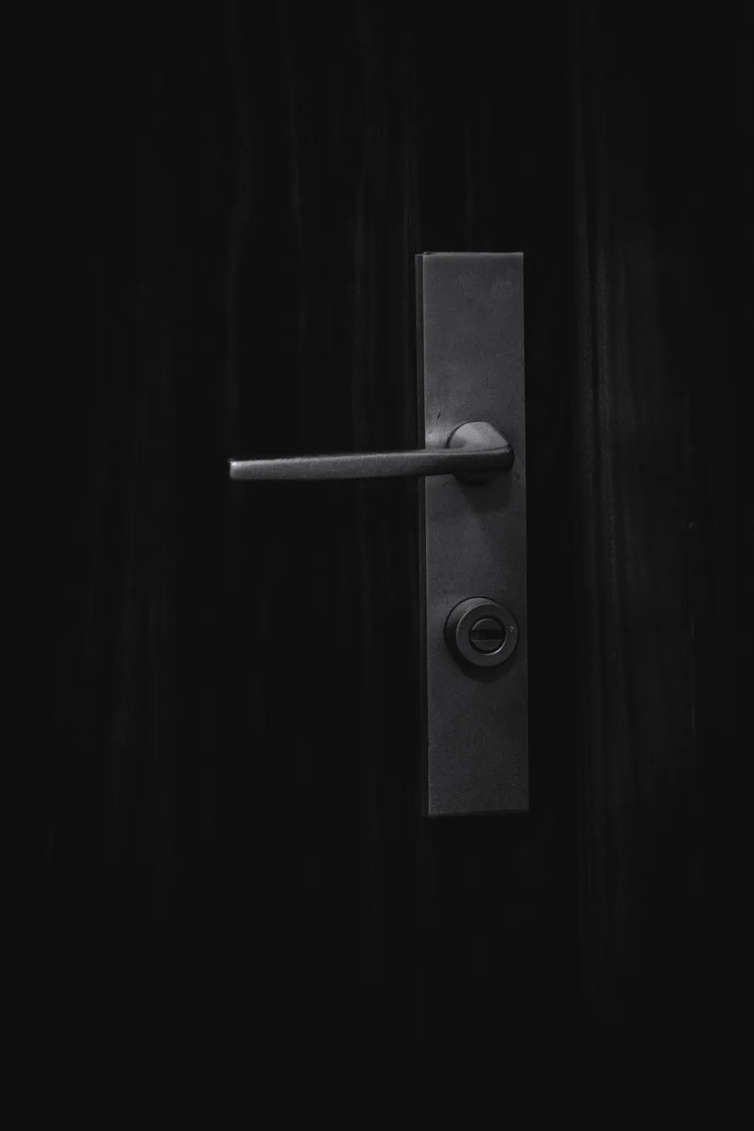 Poignée et entrée de serrure sur une porte sombre, lumière rasante
