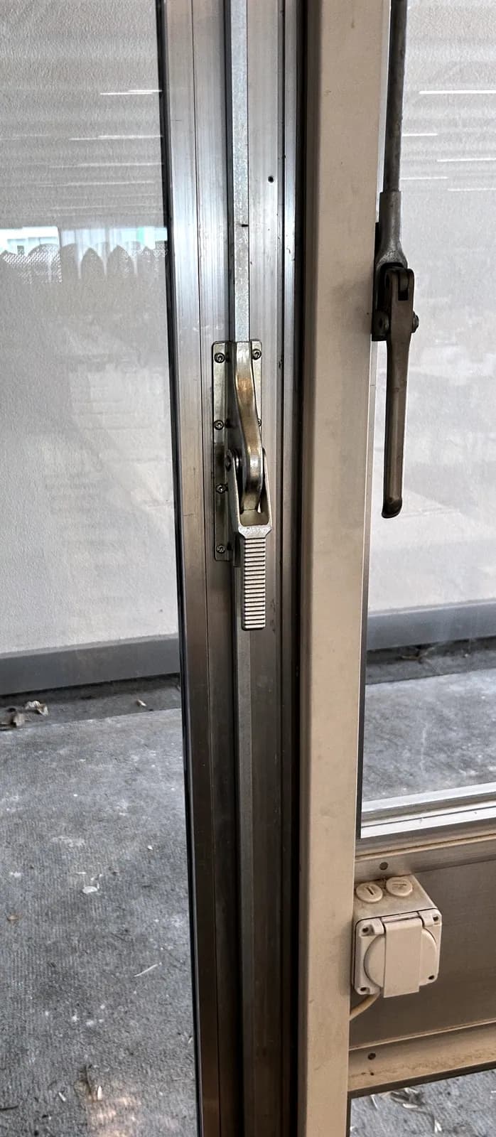 Bras de ferme-porte sur une porte vitrée, vu depuis l'intérieur