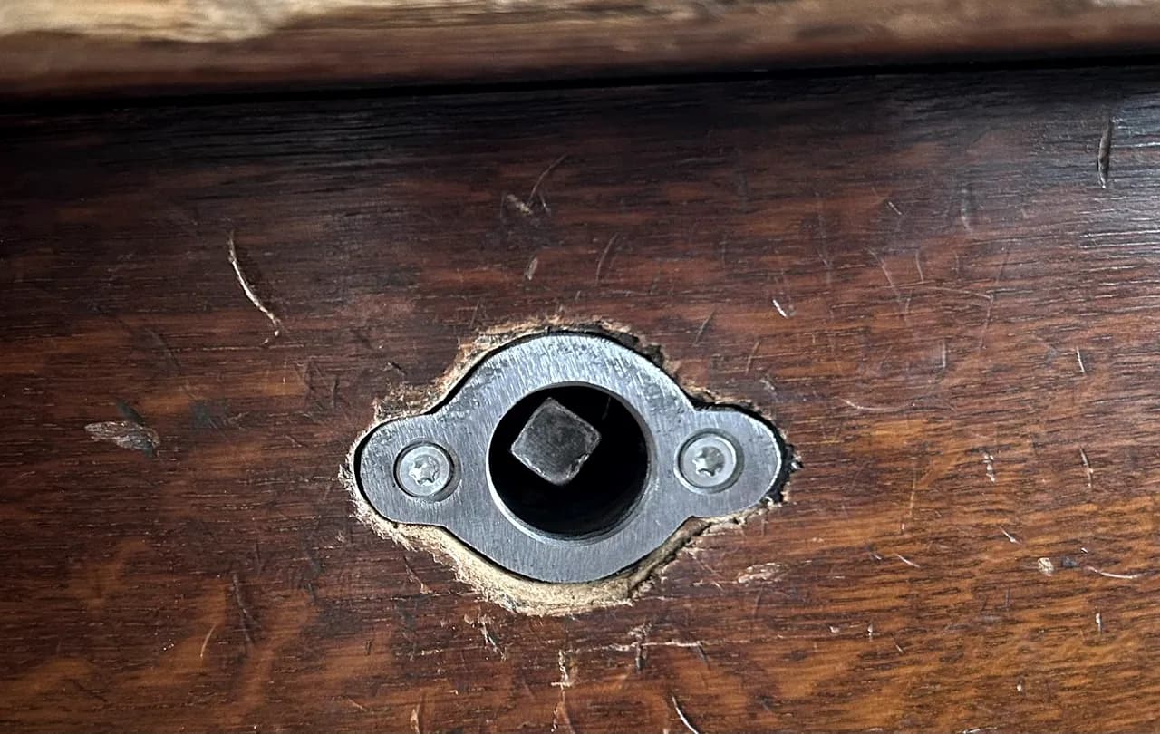 Entrée de serrure en acier encastrée dans un plateau de bois ancien