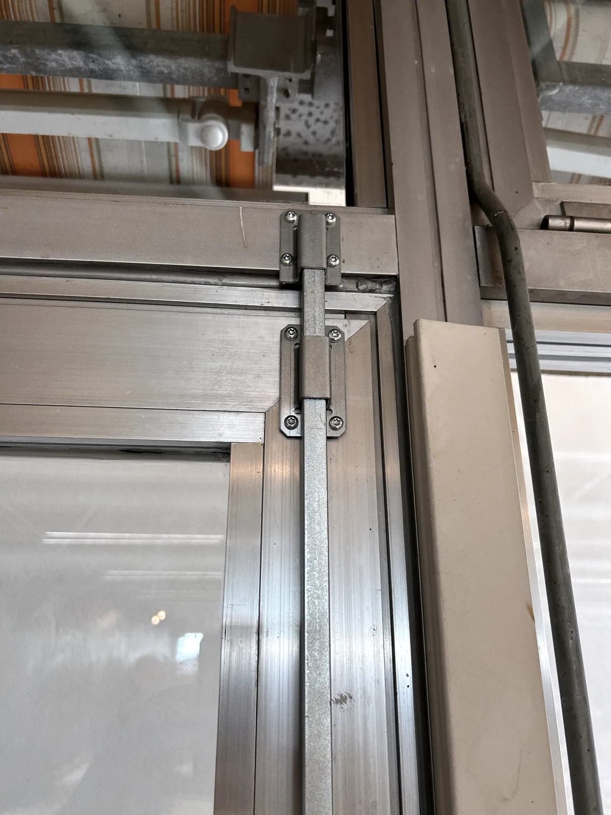 Ferme-porte et sa tringle posés sur une huisserie en aluminium