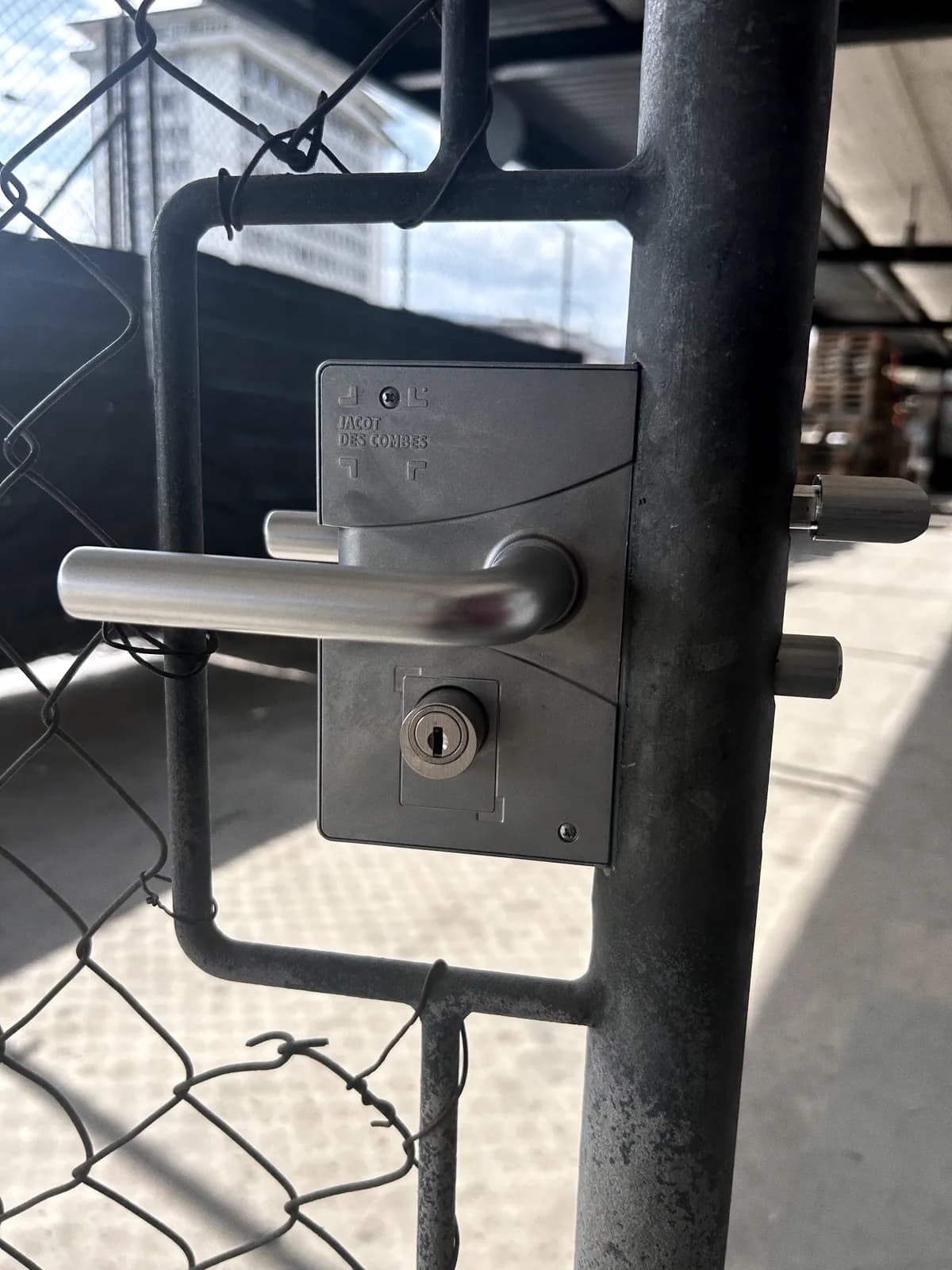 Béquille et cylindre montés sur un portillon en acier, le long d'une clôture