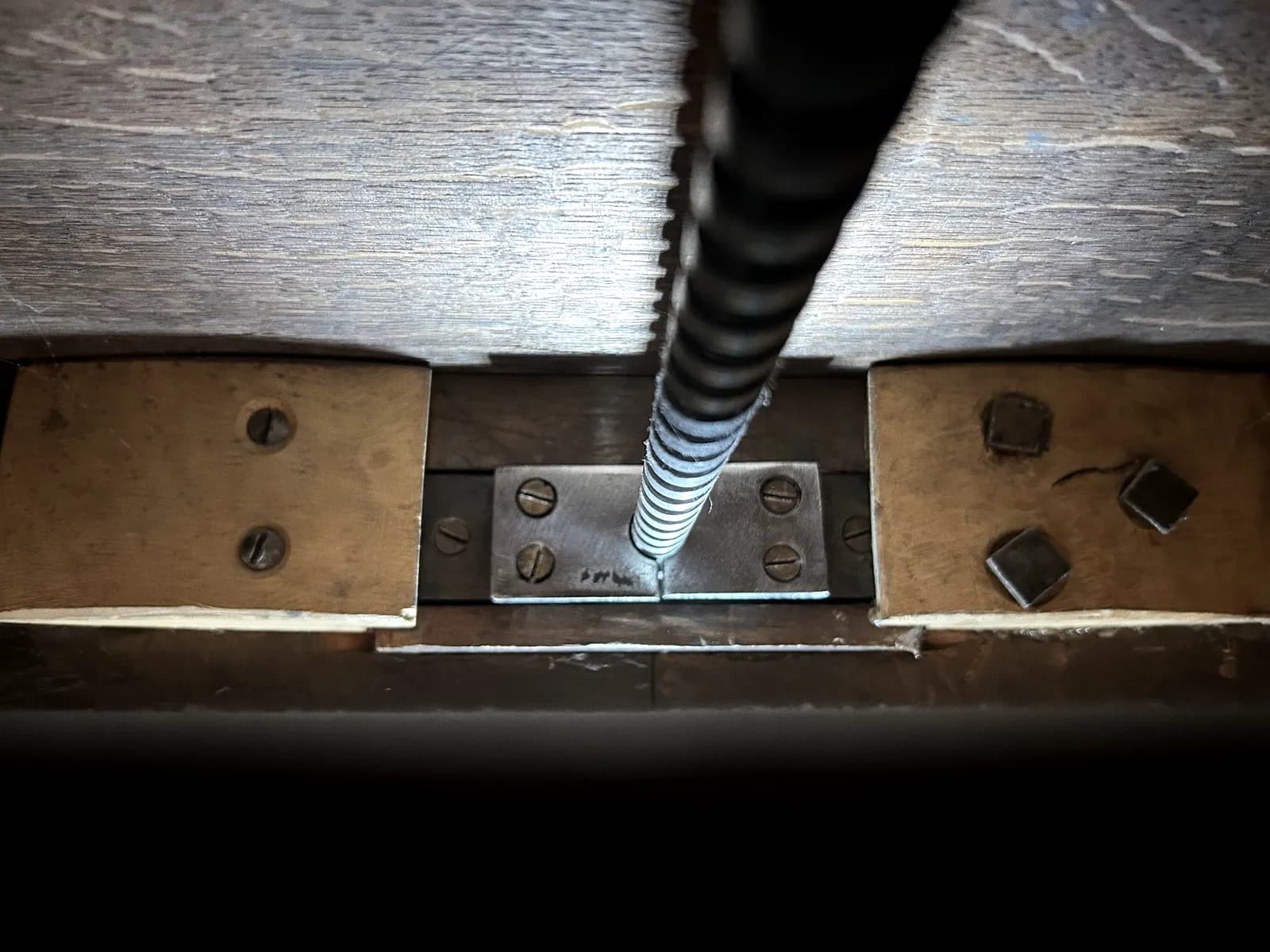 Platine d'acier boulonnée en renfort sous le piétement d'un meuble ancien